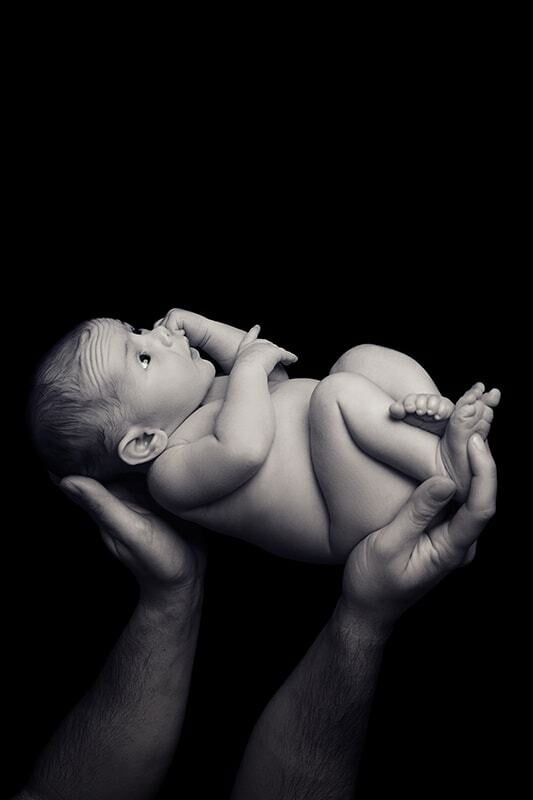 Newborn in patents hand. Black and white photo.