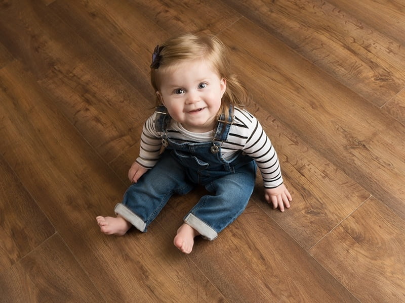 Baby Photoshoot in Croydon portrait studio. Baby sitting on wooden floor.